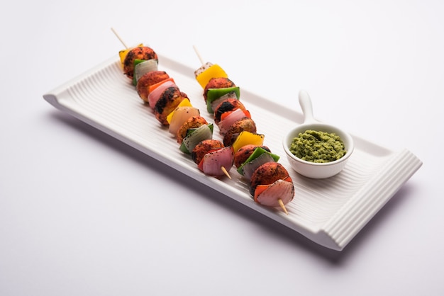 Шашлык или тандури Mushroom Tikka, подается в тарелке с зеленым чатни и кетчупом. выборочный фокус
