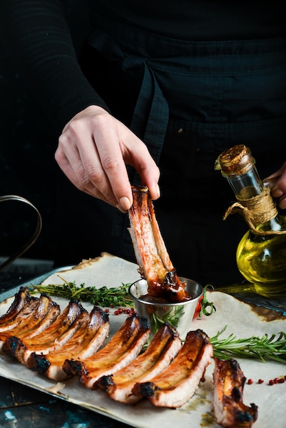 Photo barbecue tray with baked pork juicy ribs in the hands of the chef on rustic wooden background