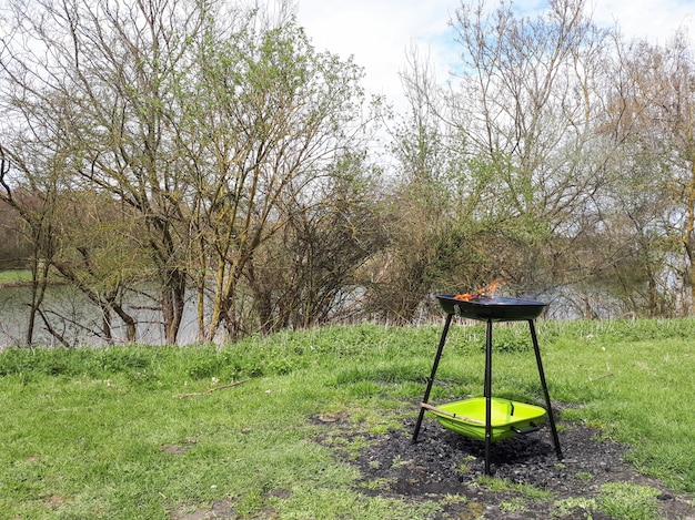 Barbecuegrill die zich bij het groene gras dichtbij de rivier bevinden