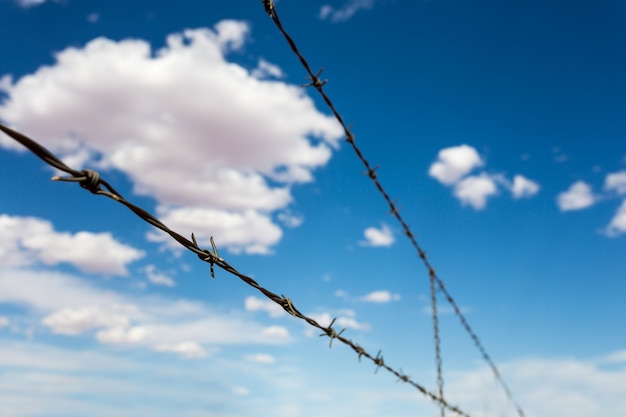 Barbed wire againdt blue cloudy sky.