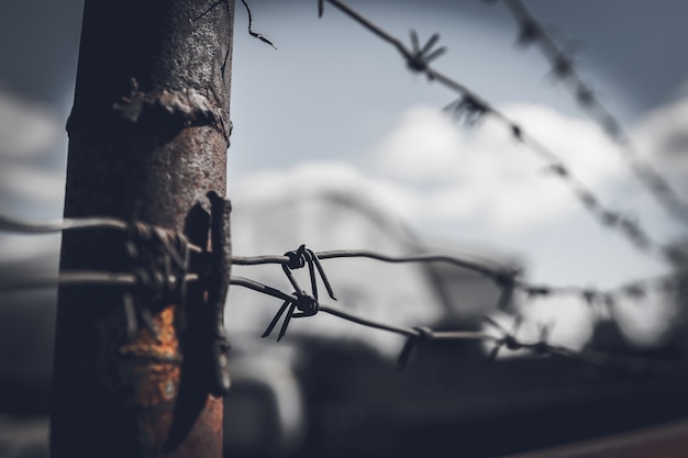 Photo barbed wire fence against dramatic, dark sky.