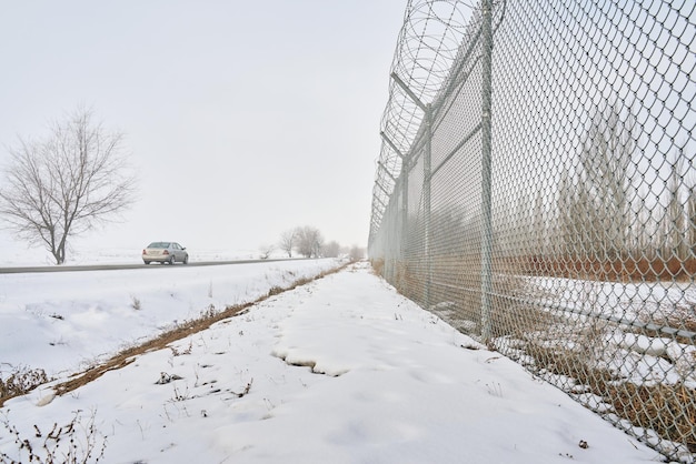 Barbed wire fence on border in winter private secured object near highway maximum security detention.