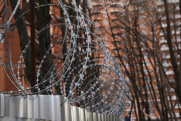 Barbed wire on the fence on the wall closeup