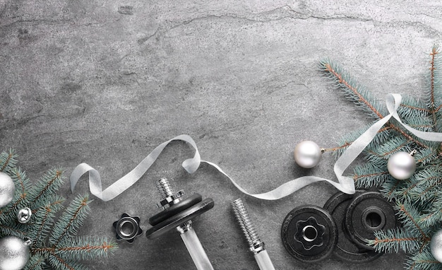 Barbell dumbbell onderdelen en kerstdecoratie op grijze achtergrond plat leg ruimte voor tekst