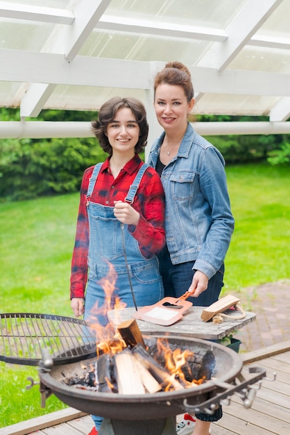 Photo barbeque party in garden with mom and her daughter at the grill in a country