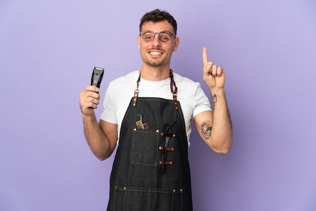 Barber caucasian man in an apron isolated on purple wall pointing up a great idea