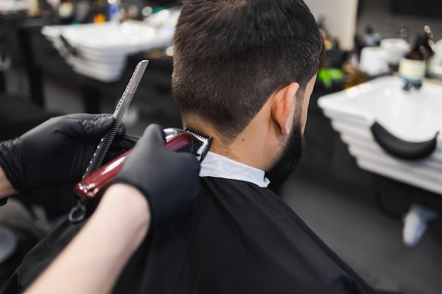 Barber cutting the back of a mans head with electric clipper