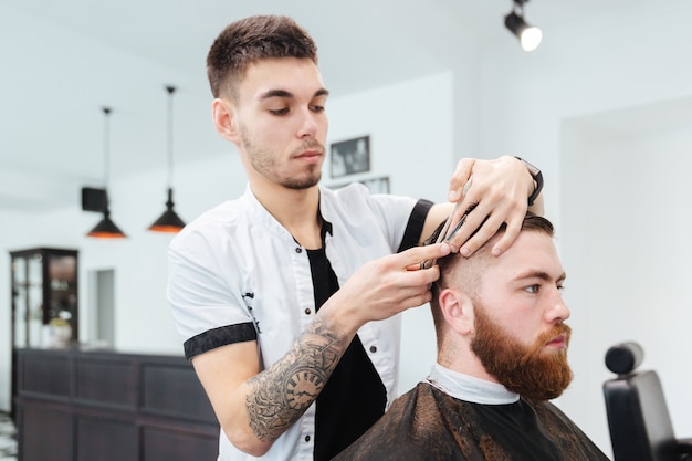 Barber cutting hair of a male client in barbershop