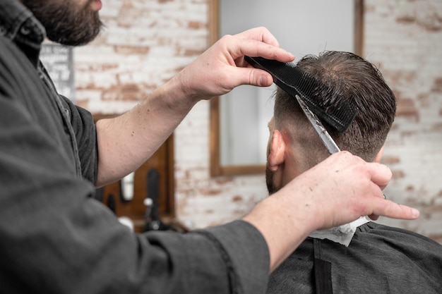 Barber cutting hair with scissors to a handsome young man High quality photography