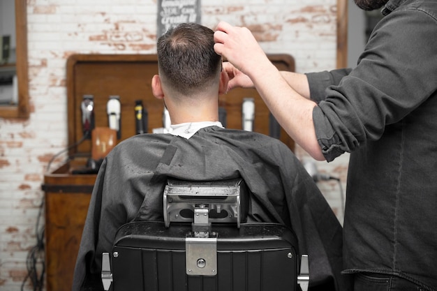 Barbiere che taglia i capelli con le forbici a un bel giovane fotografia di alta qualità