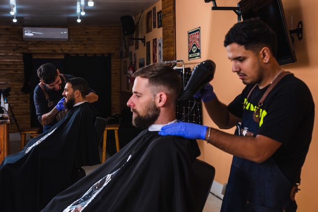 Barber drying his client's hair with a hair dryer