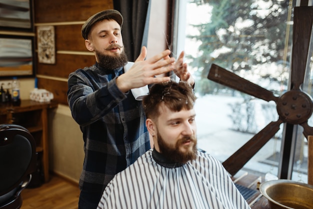 Barber in hat and bearded customer. Professional barbershop is a trendy occupation