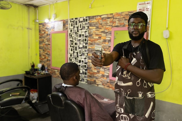 Photo a barber in his barbershop holds a razor while his customer looks at himself in the mirror