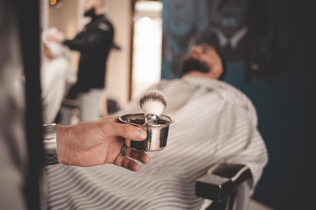 barber holding in his hand a brush for shaving