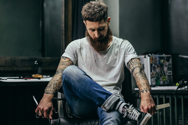 barber holding scissors and comb while sitting in the armchair