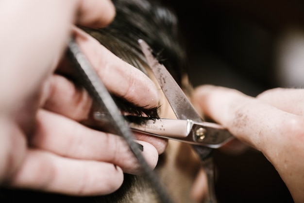 Il barbiere detiene i capelli dell'uomo nelle dita mentre lo taglia