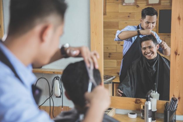 Photo barber making haircut of attractive man in barbershop