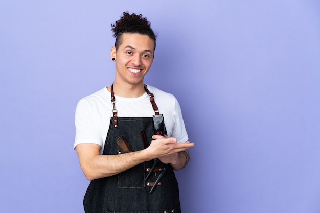 Barber man in an apron over isolated purple wall extending hands to the side for inviting to come