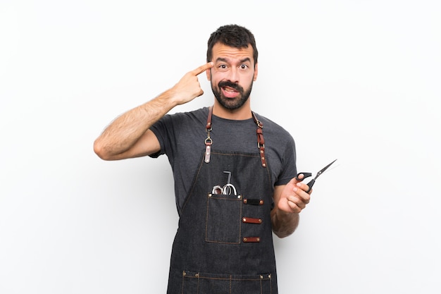 Barber man in an apron making the gesture of madness putting finger on the head