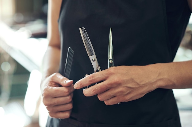 Barber scissor and hands of hairdresser in salon for grooming wellness and styling for hair service Professional tools and closeup of person in barbershop for haircare trim and cut for hairstyle