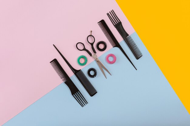 Barber set with combs and scissors on the color pink, yellow, blue paper background. Top view. Copy space. Still life. Mock-up. Flat lay