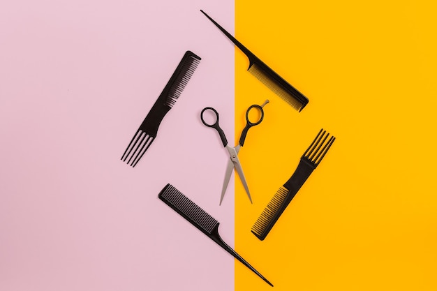 Barber set with combs and scissors on pink and yellow background. Top view. Copy space. Still life. Mock-up. Flat lay