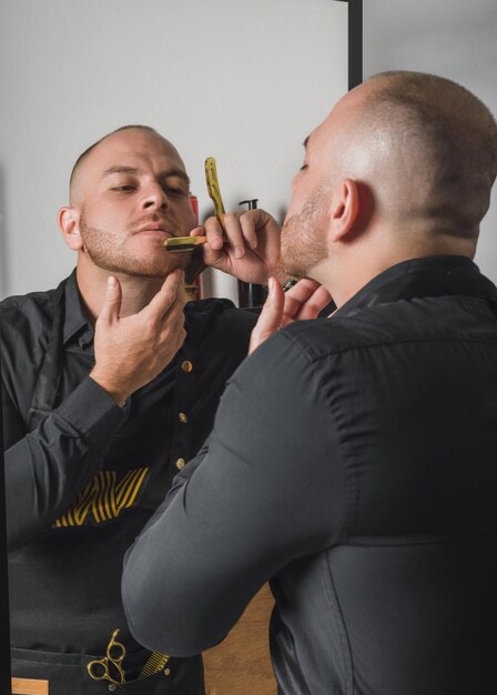 Barber shaving himself in front of the mirror