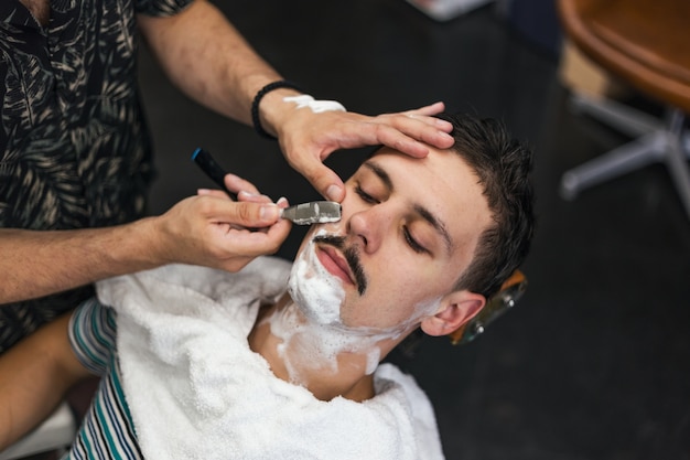 Barber shaving a man in a barber shop
