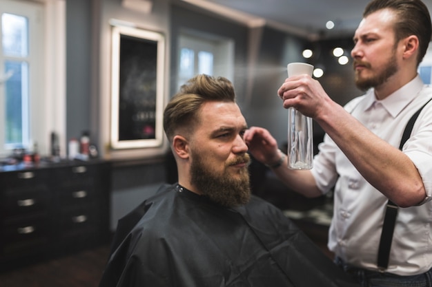 Photo barber spraying hair of customer