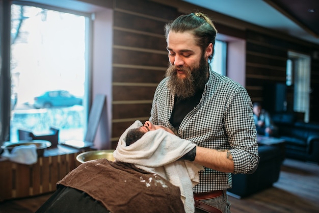 Barber wiping the client beard with a towel