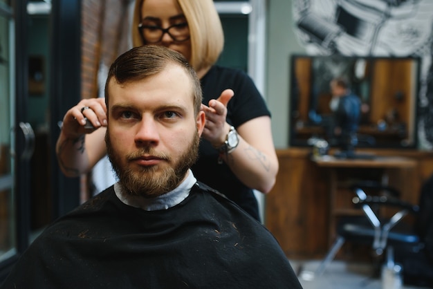 Photo barber woman cutting man hair at the barbershop. woman working as a hairdresser. small business concept.