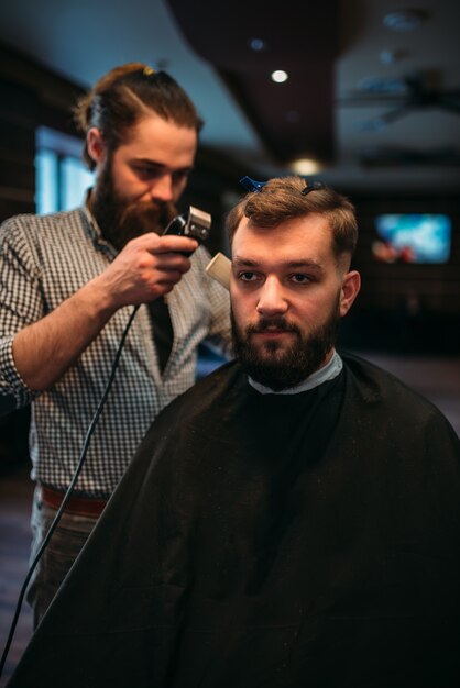 Barber working by clipper with hairstyle of client