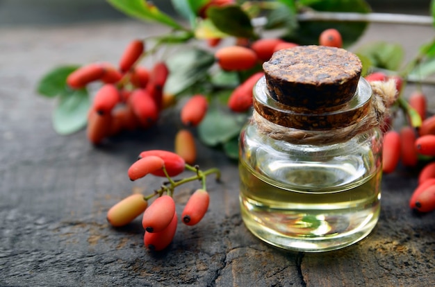 Olio essenziale di crespino in una bottiglia di vetro sul vecchio tavolo in legno per aromaterapia cura della pelle o spa berberis vulgaris estratto di erbe