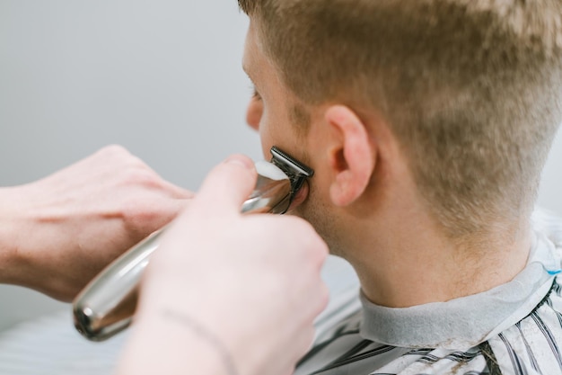 Barbershop concept Work of a male hairdresser Background Hairdresser cuts hair of blond man