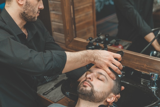 Barbershop, a man is washed his hair. Barber washes his client. Wash hair and beards after cutting. Personal care