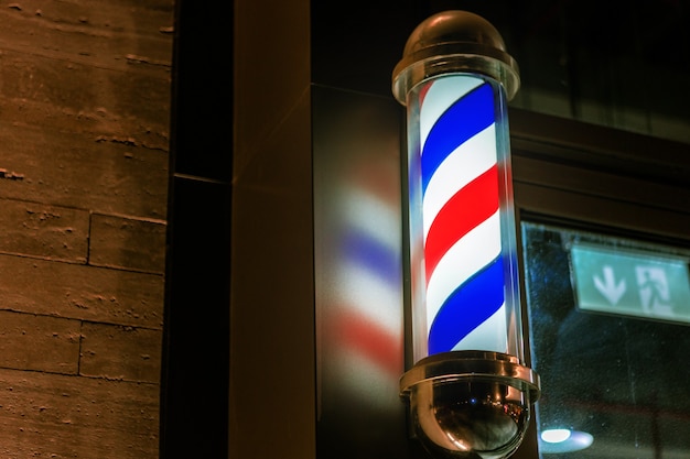 Photo barbershop pole sign attached to a wall of building