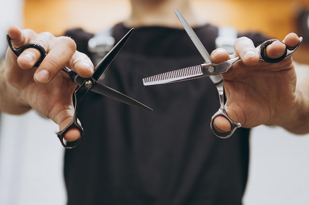 Photo barbershop stylish man holds barber shop scissors hairdresser with razor for shaving barber shop equipment vintage salon tools for barber shop beauty industryskin care concept shears scissors