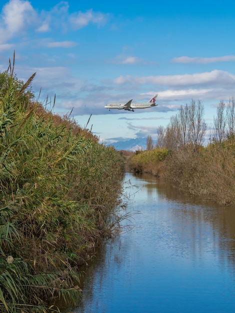 Barcelona spain december 16 2022 qatar airways plane landing at barcelona airport views in front of the llobregat de