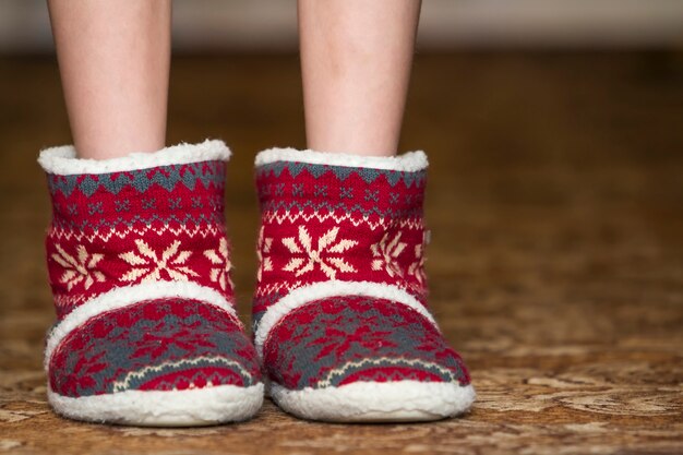 Bare child legs and feet in red winter christmas boots