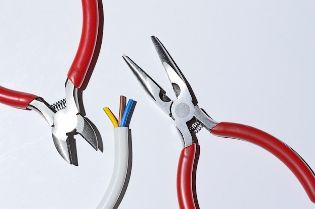 Bare electric wire, wire cutters and pliers not against a light background. Verkhnyts view.