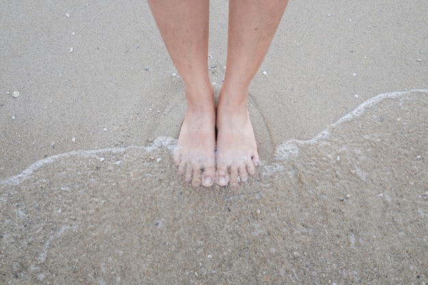 Foto piedi nudi in piedi sulla spiaggia