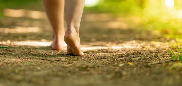 Bare feet of a woman walking along a trail in the woods