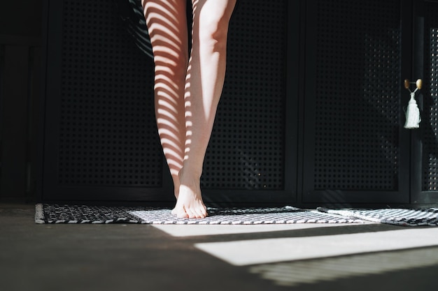 Bare feet of young woman in the bathroom at home light and shadow