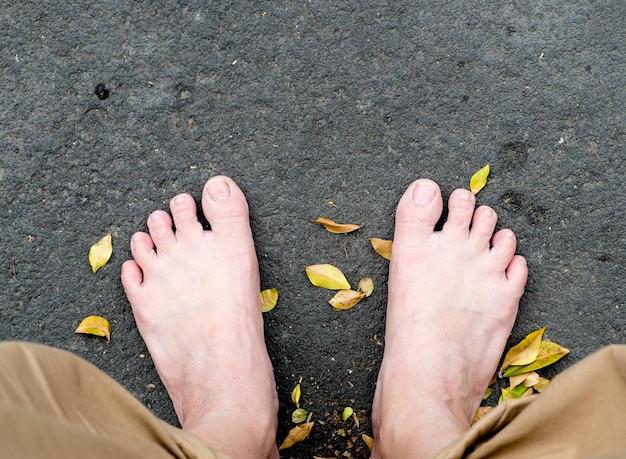 Photo bare foot on black stone and dried leaves