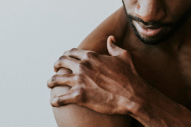 Bared chest black man touching his shoulder