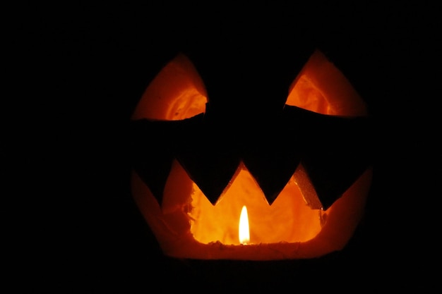 Photo bared teeth of halloween pumpkin ghost with burning candle within