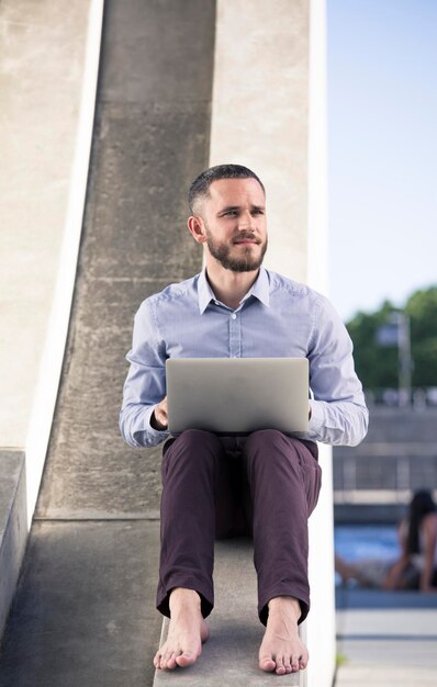 Barefoot businessman using laptop outdoors