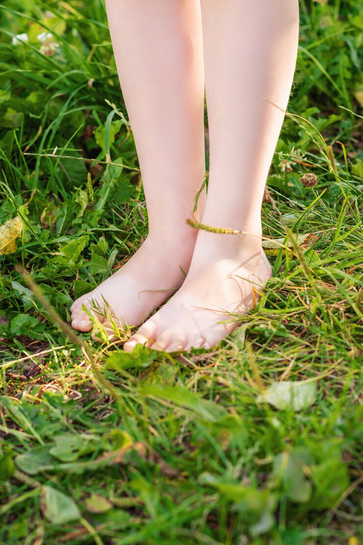 Barefoot of child standing on green grass.