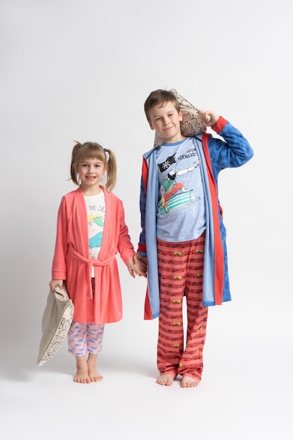 Premium Photo Barefoot children brother and sister in pajamas with pillows in their hands Boy and girl posing together on a white background