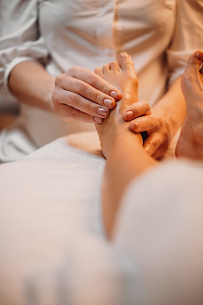 Barefoot client is having a massage session in a professional spa salon for her legs